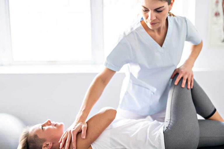A chiropractor assists a young athlete with gentle joint movement on a padded examination table.