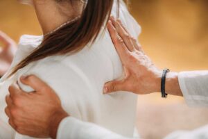 A chiropractor explains a spine model to an adult patient in a bright clinical room.